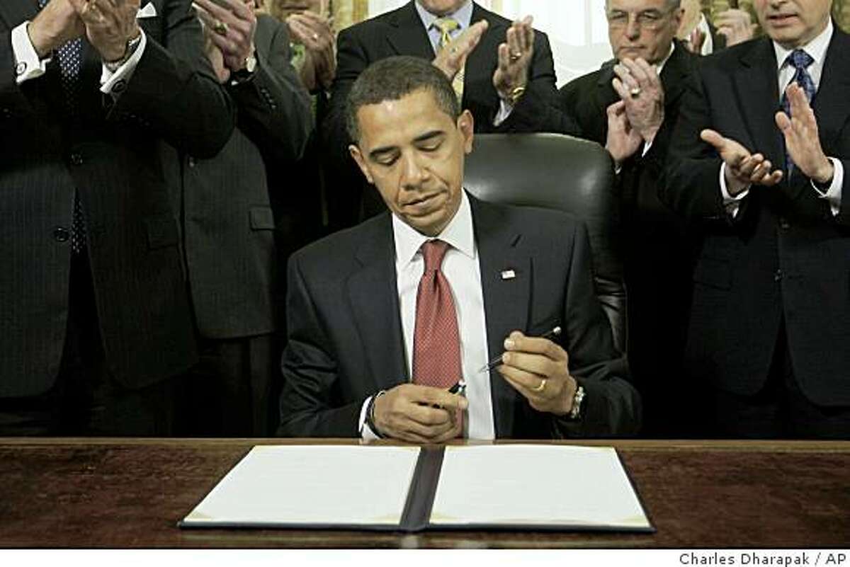 President Barack Obama is applauded as he caps his pen after he signed an executive order closing the prison at Guantanamo Bay, Thursday, Jan. 22, 2009, in the Oval Office of the White House in Washington. The president is applauded by retired military officers. (AP Photo/Charles Dharapak)