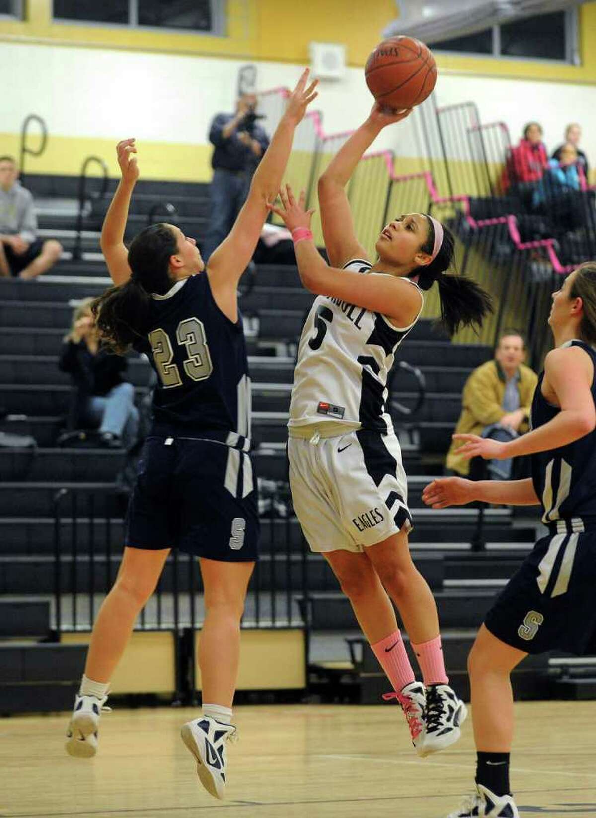 Trumbull's #5 Joyce Woolen, right, attempts a shot as Staples' #23 Sophie deBruijn defends, during girls basketball action in Trumbull, Conn. on Friday February 10, 2012.