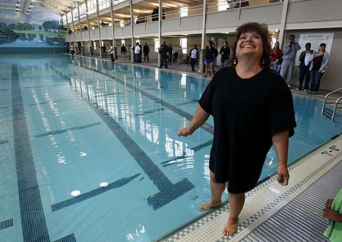 Rosemary Fonseca uses her toes to check the temperature moments before the Richmond Plunge reopened to swimmers Saturday. Fonseca, who was manager when the Plunge closed in 2001, was one of the first to jump into the pool.
