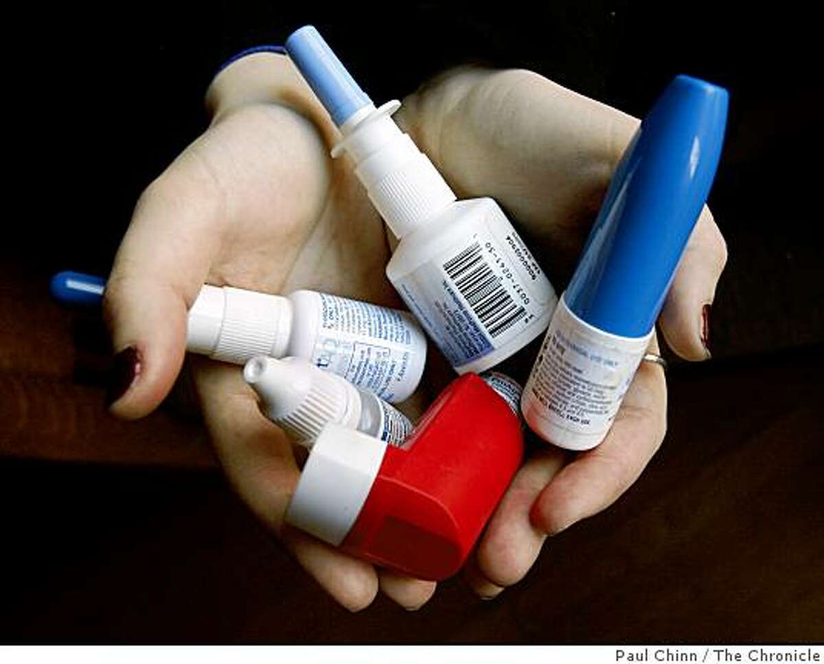 Jessica Palmer cradles her collection of medication in Emeryville, Calif., on Wednesday, Dec. 17, 2008. Palmer, who needs the prescription sprays and inhalers to control an allergy condition, faces expensive health insurance costs after getting laid off from her job in late October.