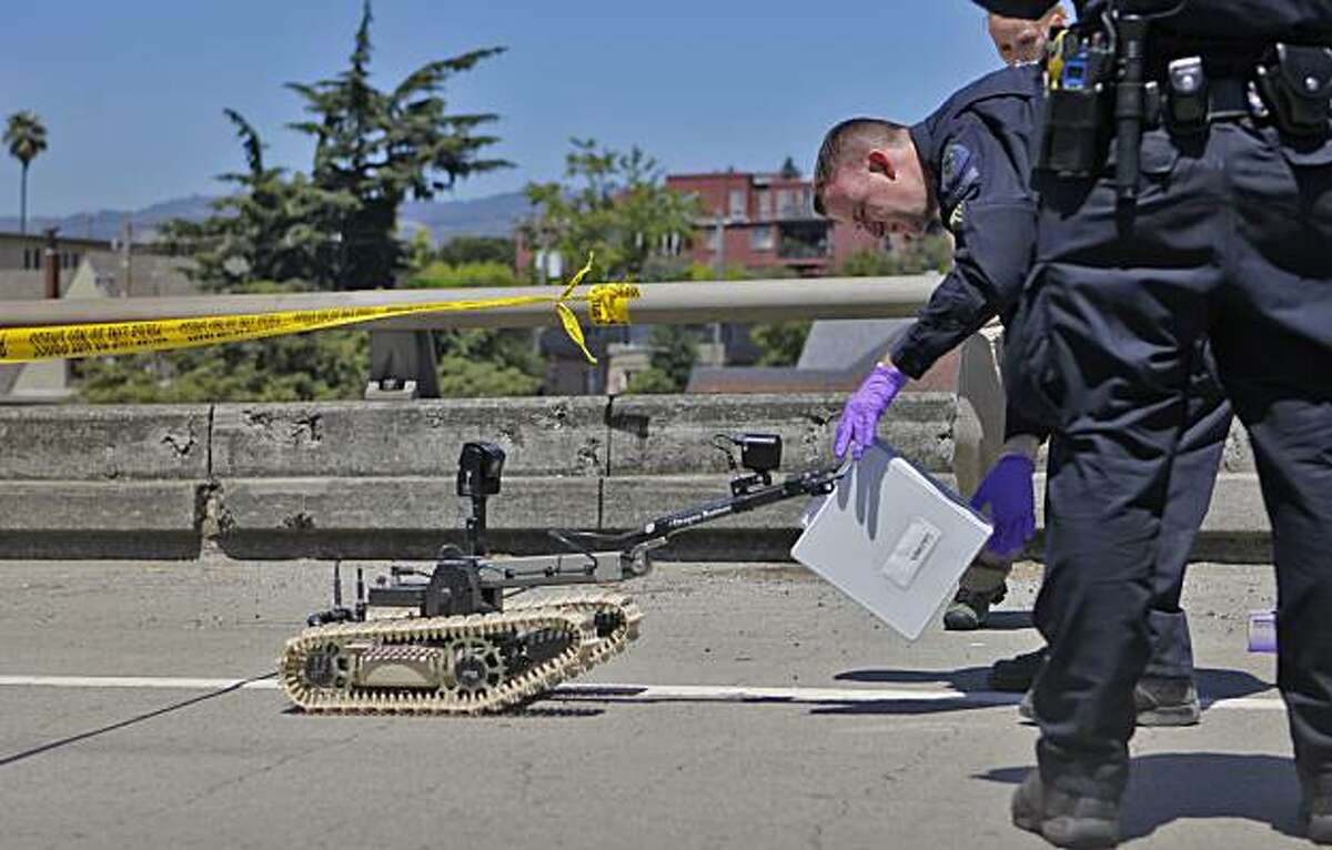 Alameda County Bomb Squad Sgt. Ray Kelly takes evidence the squad's robot retrieved from the shootout suspect's truck Sunday in Oakland.