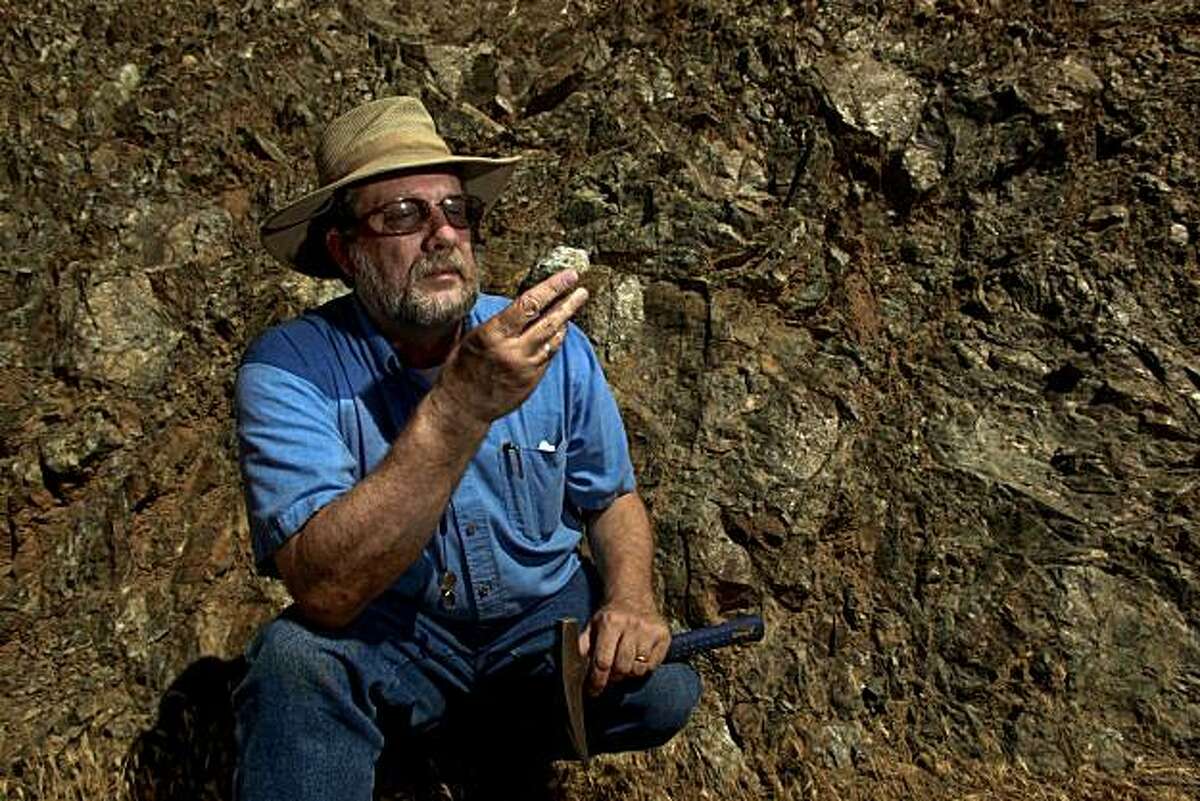 Garry Hayes, Professor of Geology at Modesto Junior College, holds a sample of Serpentine against a solid outcropping of the rock, found along Del Puerto Canyon Road, 20 miles west of Patterson, Ca. on Thursday July 15, 2010. A bill to remove serpentine as California's official state rock was working its way through the state legislature until geologists heard about it and are now taking offense to the proposal. The bill sponsored by a woman whose husband died of asbestos poisoning is supposed to be a symbolic gesture given that serpentine is the source of asbestos.