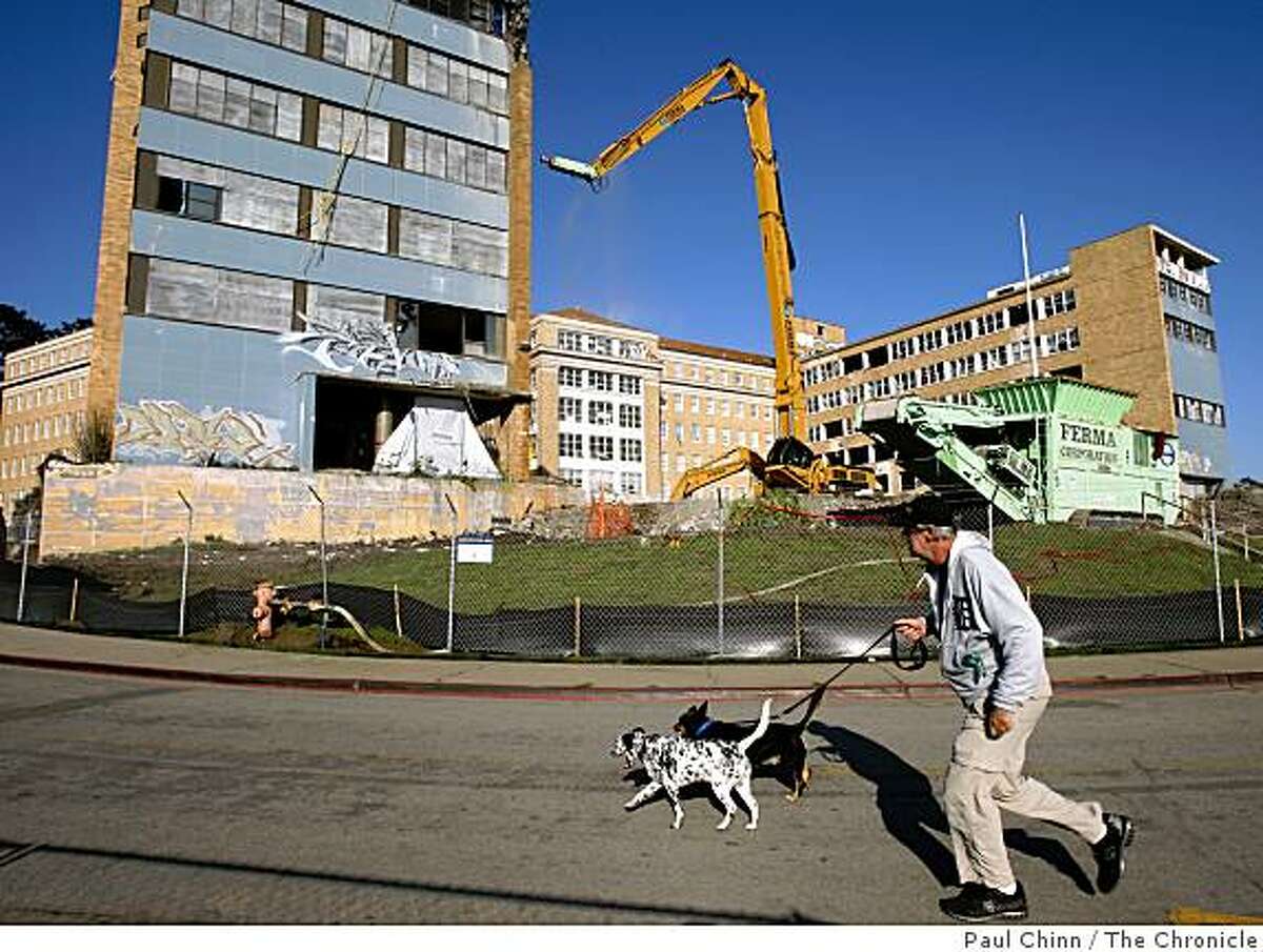 Mick Gast walks with Riley and Pup Pup past the long-abandoned Public Health Service Hospital at the Presidio where crews began demolishing the two wings in San Francisco, Calif., on Thursday, Dec. 4, 2008.