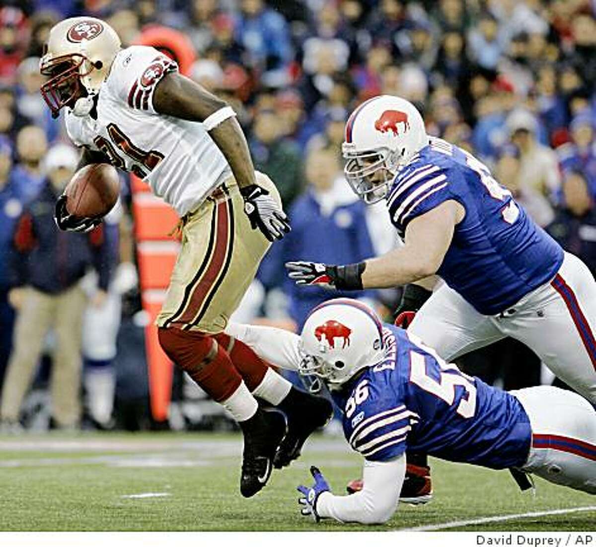 San Francisco 49ers' Frank Gore (21) runs under pressure from Buffalo Bills' Kyle Williams, right, and Keith Ellison (56) during the first half of the NFL football game at Ralph Wilson Stadium in Orchard Park, N.Y., Sunday, Nov. 30, 2008. (AP Photo/David Duprey)