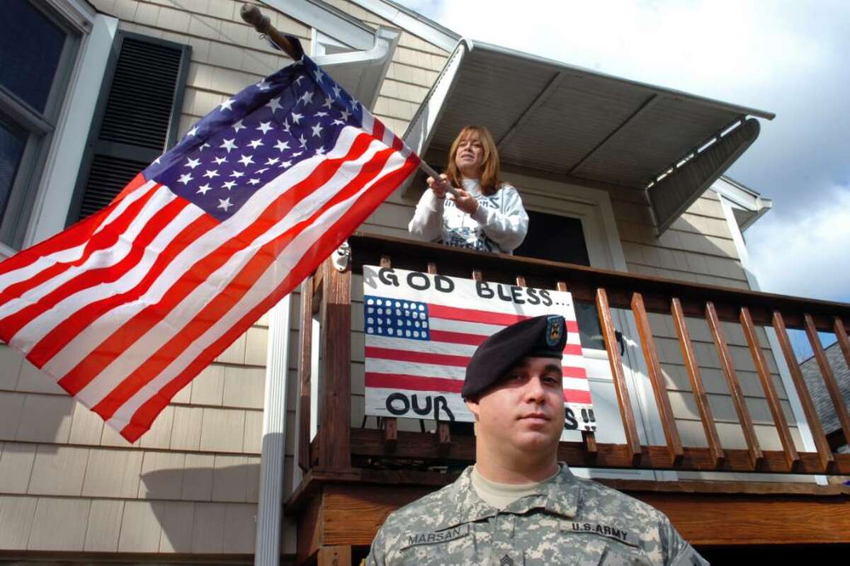Staff Sgt. Nick Marsan of the Connecticut Army National Guard poses as his mother, Debbie, hangs a flag in front of the family home in Fairfield, Conn. on Nov. 6th, 2009. Marsan will deploy to Afghanistan with the 102nd Infintry later this month.
