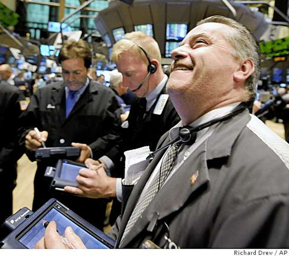 Trader Thomas Riley, right, smiles as he works on the floor of the New York Stock Exchange, Monday Oct. 13, 2008. Wall Street stormed back from last week's devastating losses Monday, sending the Dow Jones industrials soaring a nearly inconceivable 936 points after major governments' plans to support the global banking system reassured distraught investors. (AP Photo/Richard Drew)