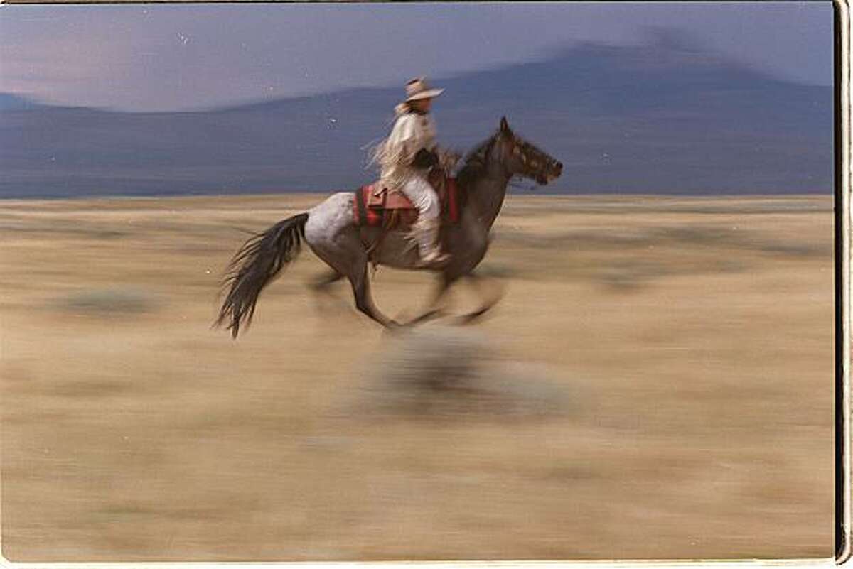 "Sagecreek Annie" rides "Smokey," a grey-blue horse on the Pony Express trail in a re-enactment near Cody, Wyoming.