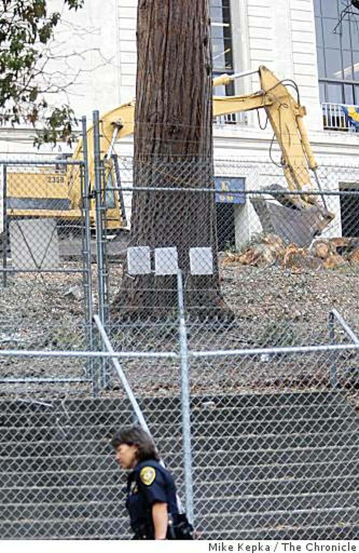A U.C. Berkeley police officer walks past the last standing tree near what was once a grove of oaks and redwoods on the site of U.C. Berkeley's new sports complex, wave from their perch on Monday Sept. 8, 2008 in Berkeley, Calif. After two years of protest 4 tree sitters still remain in the tree.