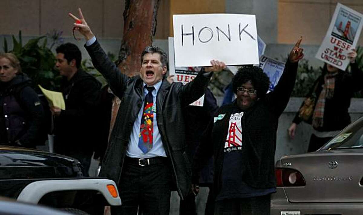 Antonio Mankini and Bobbie Washington yell to commuters to honk in protest of school budget cuts Tuesday in San Francisco.