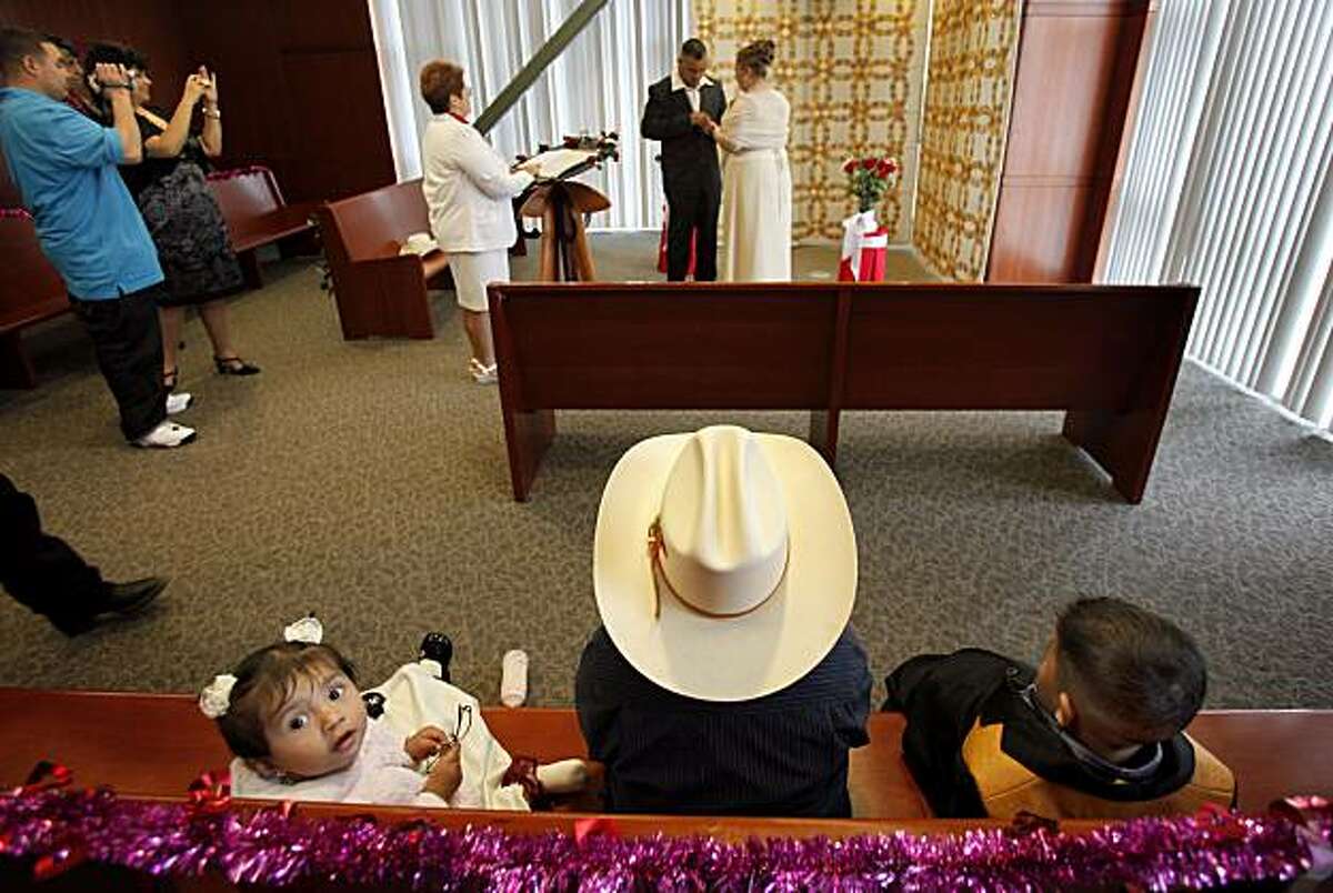 Ashley Alonso, left, Andres Gonzalez, in cowboy hat, and Victor Alonso watch their relatives Victor Alonso-Martinez and Marylu Gonzalez get married on Valentine's Day at the Alameda County clerk recorders offices in downtown Oakland.