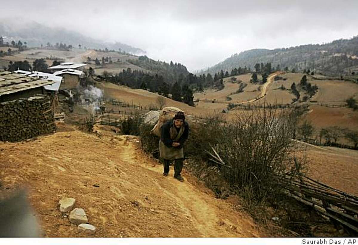 A local man carries a load on his back as he walks on an ancient trail that passes through the remote village of Signyar in Bhutan, Saturday, March 8, 2008. Even in this remote mountain kingdom that has held out against the modern world as long as it could, times are rapidly changing as old beliefs yield to the modern ways of life. (AP Photo/Saurabh Das)