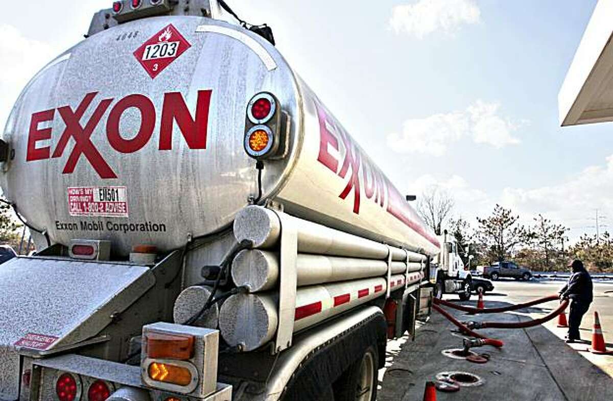 FILE - In this Jan. 30, 2009 file photo, an Exxon tanker truck operated by Corey Moorer, right, of Clinton, Md., makes a refueling stop at an Exxon station in Arlington, Va. Exxon Mobil said Monday, Feb. 1, 2010, its fourth-quarter earnings tumbled 23 percent as higher oil prices squeezed profit margins in its refining business.