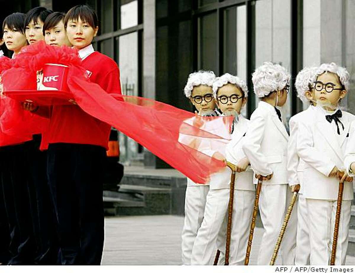 Beijing, CHINA: Chinese children (R) dress up as US fastfood chain Kentucky Fried Chicken's Colonel Sanders look-alikes during a store opening ceremony in Beijing, 12 April 2006. As China's economic transformation brings more wealth to many of the nation's 1.3 billion residents, many are spending more on food, as last year Chinese spent 780 yuan (96 USD) per capita on food, 135 times more than in 1978, when the country was beginning to emerge from the Cultural Revolution. AFP PHOTO (Photo credit should read AFP/AFP/Getty Images)