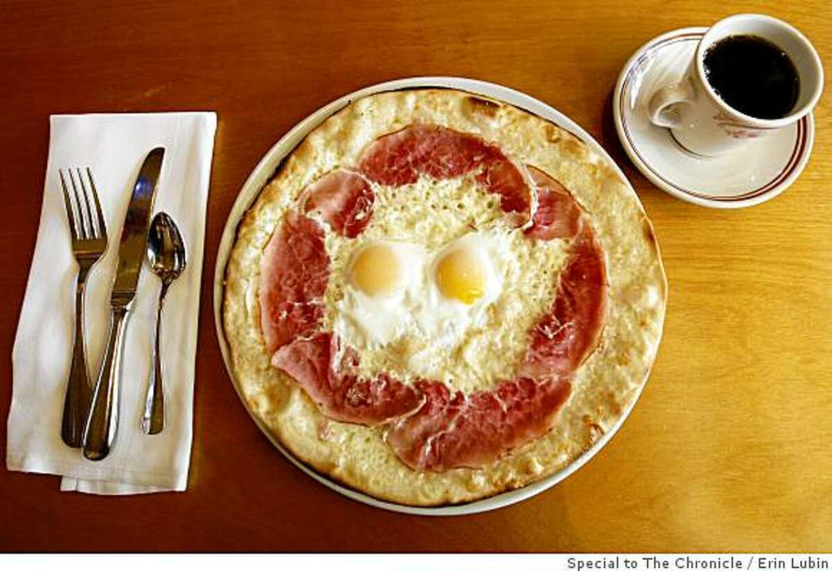A breakfast pizza of fontina cheese, smoked ham, and eggs sits on a table at Rose's Cafe on Union Street in San Francisco.