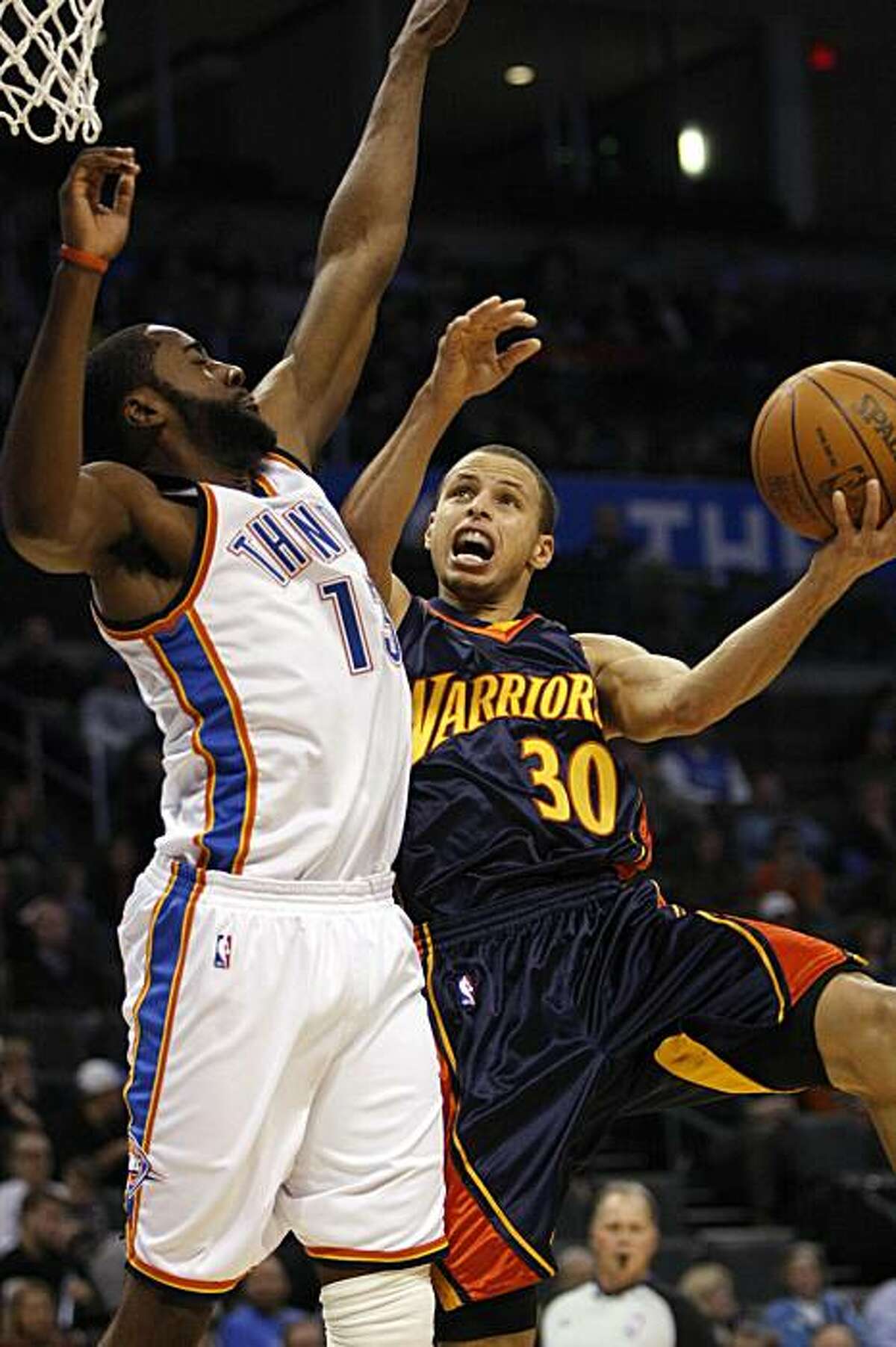 Golden State Warriors guard Stephen Curry goes up for a shot as Oklahoma City Thunder's James Harden defends in the first half in Oklahoma City on Monday.