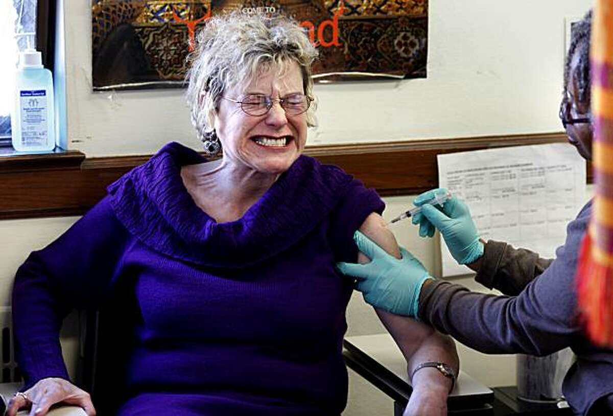 Lisa Watson RN (far right) gives a standard flu shot to Carolyn Eder of San Francisco who was glad they were available. The standard flu shots are still being given out at Dept. of Health in San Francisco on a daily basis.