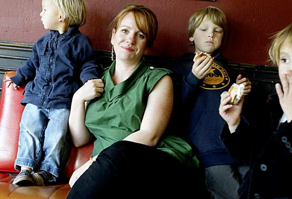 Dawn Miller, owner of a web site Alice & Isa, that carries only locally made women's and men's apparel, accessories and jewelry. In the photograph with her sons (Keegan (8), Finn (6), and Boone (2) at Velo Rouge Cafe, where she often takes her laptop to work on the website, and where she also hosts a monthly fashion film series. Friday, November 13, 2009. San Francisco Calif.