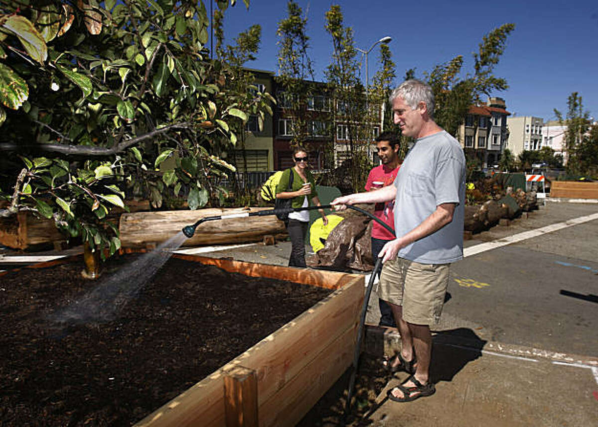 Jeff Goldberg, who worked on the temporary park as a volunteer, waters the plants in the new park while talking with Pablo Woythaler (center), and Jessica Donohue (left) in San Francisco, Calif. on Wednesday, September 16, 2009.