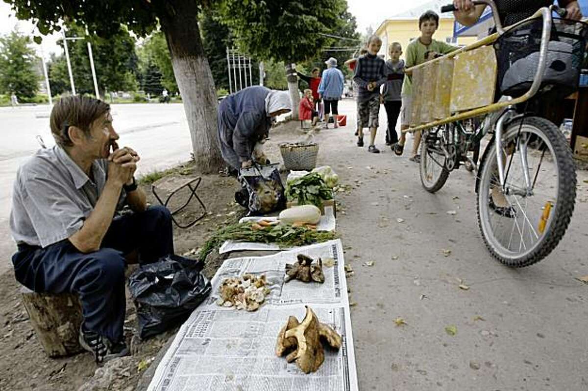 This Aug. 5, 2009 photo shows a man selling mushrooms in downtown Yasnogorsk, Russia. The Yasnogorsk Machine-Building Factory stamped out thousands of pounds of steel and iron into parts for wagons, pumps and locomotives for Russia's mining industry, but the factory that this town grew up around, is on its last breath, choked by a global recession that has shaken Russia to the core. (AP Photo/Misha Japaridze)