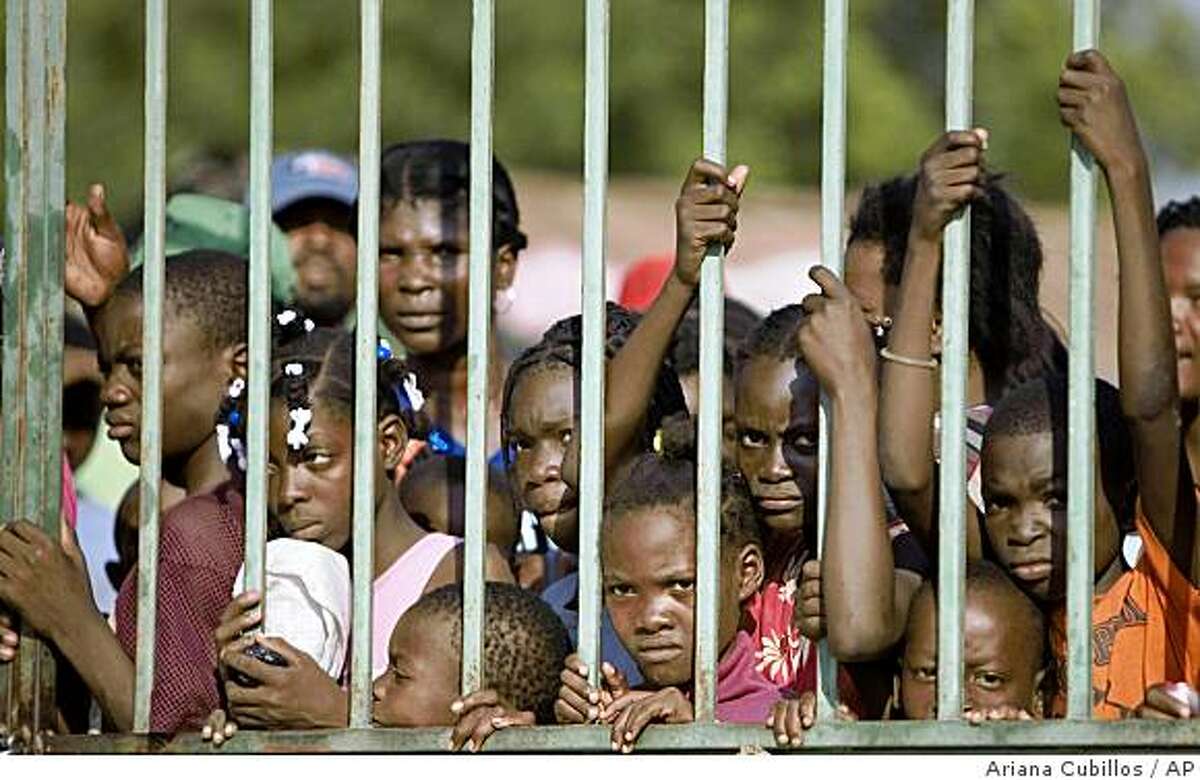 ** CORRECTS THE FACT THAT FOOD WAS DONATED BY THE VENEZUELAN GOVERNMENT ** Children wait outside a church, where aid workers were giving out bags of food donated by the Venezuelan government, in Port-au-Prince, Friday, April 18, 2008. Hundreds of Haitians stood in long lines Saturday, just as others had walked for hours throughout the week to receive the U.N. and regional food aid pouring into the country after a spate of deadly riots.(AP Photo/Ariana Cubillos)