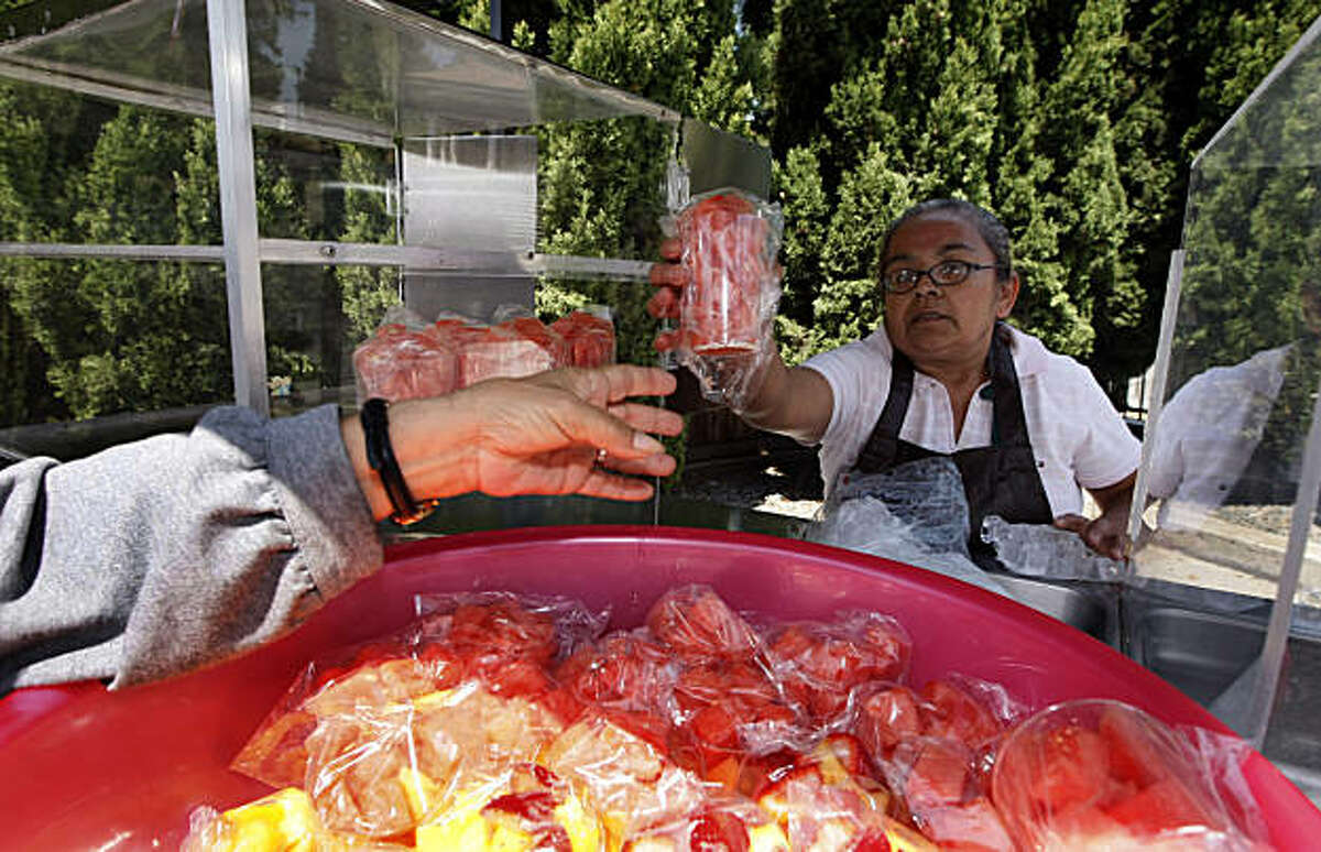 Food vendor Cecilia Lopez loads her food cart with fresh fruit cups in preparation for Oakland's Eat Real Festival on Aug. 29-30 in Oakland.