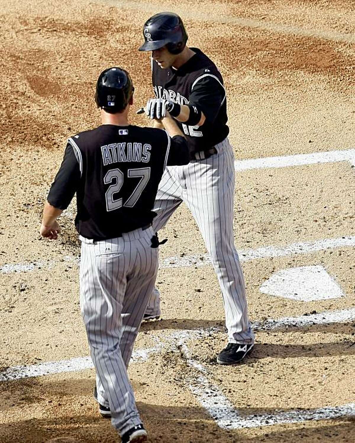 Colorado Rockies' Garrett Atkins (27) and Clint Barmes (12) celebrate Barmes' two-run home run in the second inning of Game 2 of a baseball doubleheader against the Florida Marlins on Sunday, Aug. 16, 2009, in Miami. (AP Photo/J Pat Carter)