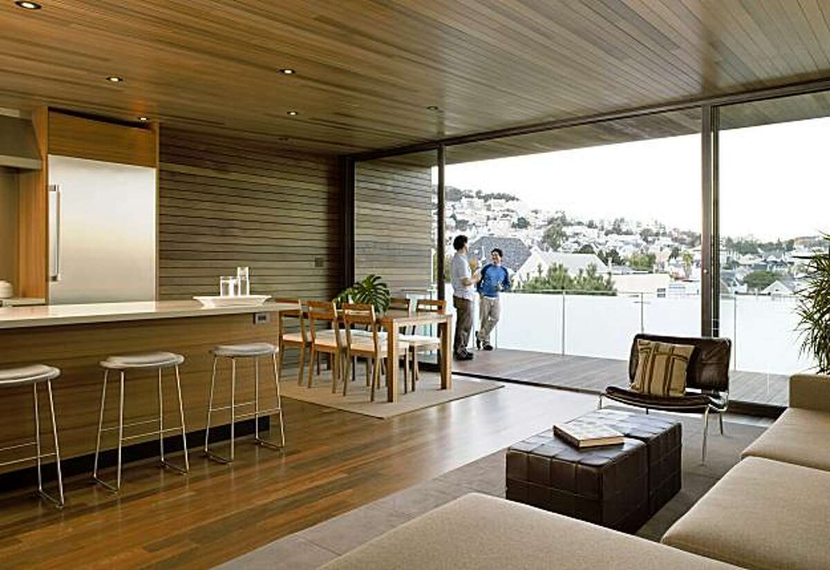 Open-plan living room and kitchen on the top floor of the 1960s house remodeled by Terry & Terry Architecture in Noe Valley. The tube-like interior is fully clad in ipe wood. A central skylit stairway conects and illumintaes all three floors of the Noe Valley tube-shaped house designed by Terry & Terry Architecture