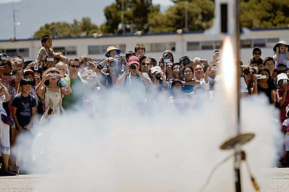 Moonfest attendees watches a scaled model of a Saturn V rocket takes off from the Moffett Federal Field runway during Moonfest in commemoration of the 40th anniversary of the lunar landing during Moonfest held at Ames Research Center in Mountain View, Calif. Sunday, July 19, 2009.