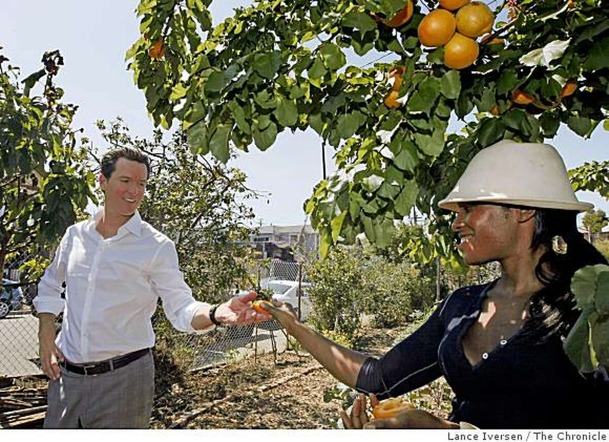 Abeni Ramsey a west Oakland Community Farm Coordinator hands Mayor Newsom a ripe apricot during his tour of Wow West Oakland Woods Farm. Wednesday July 8, 2009