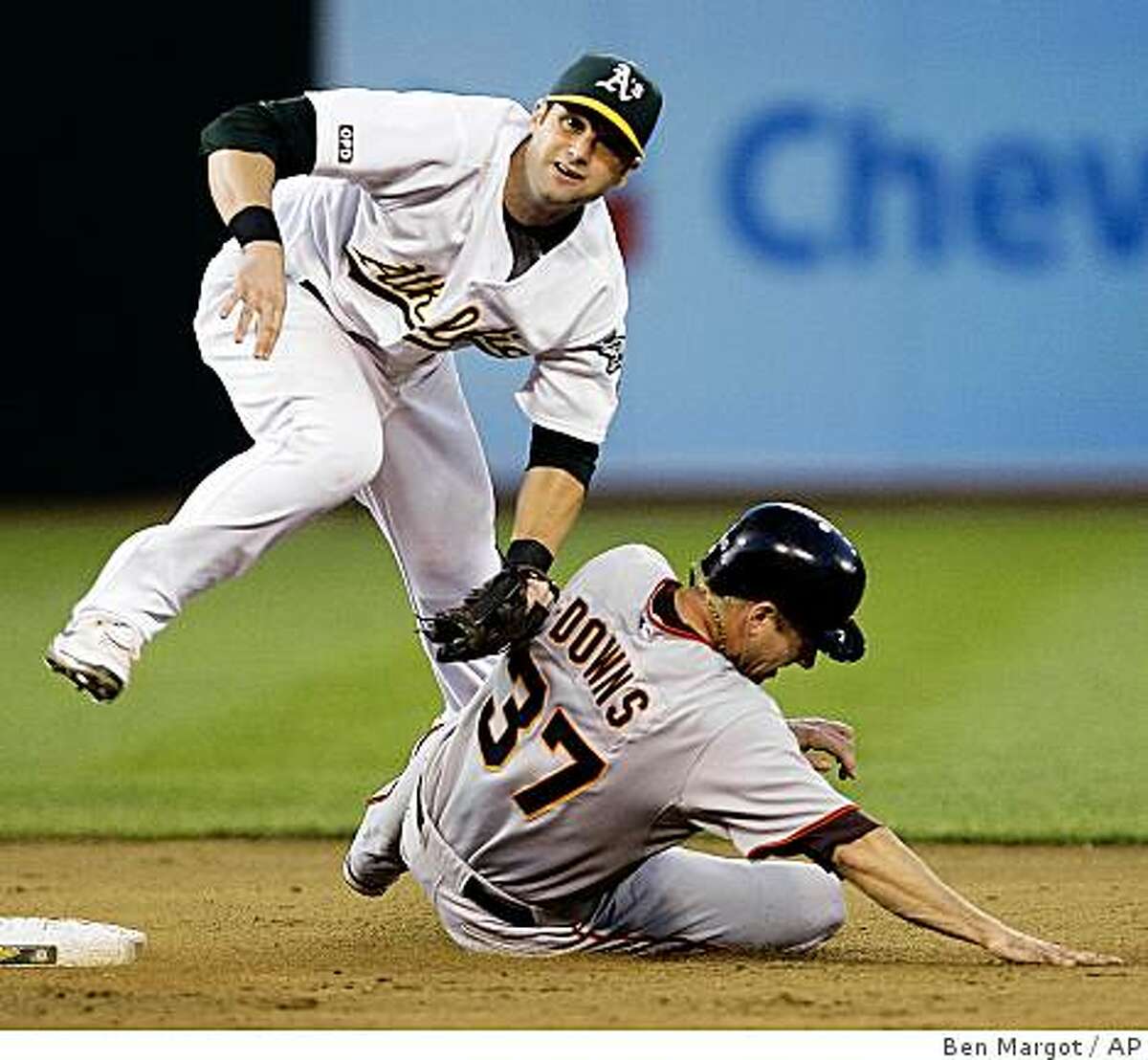 Oakland Athletics second baseman Adam Kennedy hops over San Francisco Giants' Matt Downs (37) after completing a double play in the fifth inning of a baseball game Monday, June 22, 2009, in Oakland, Calif. Giants' Aaron Rowand was out at first base. (AP Photo/Ben Margot)