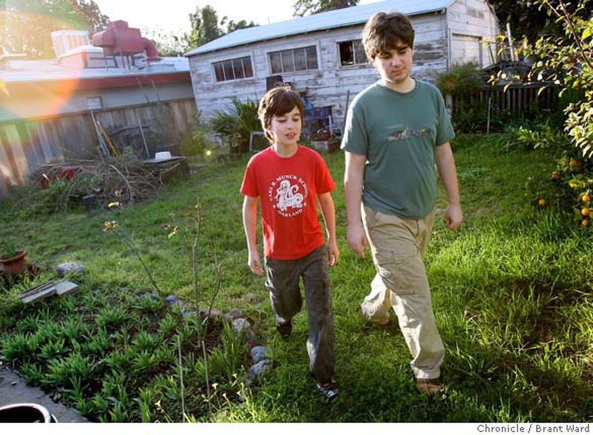 Alexander, left, and Kenton Barks walk through the backyard that used to contain a garage. The Barks family tore down a garage in their backyard in Oakland planning to build a family music studio, but the value of the house was so low that they must put their plans on hold now. (Photo by Brant Ward/San Francisco Chronicle)