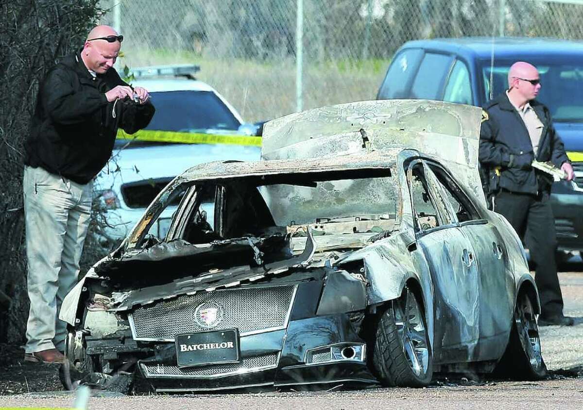 Law enforcement officials examine a burned Cadillac CTS Thursday, Feb. 9, 2012 in Waco, Texas that belonged to former Churchill High School football player, Eagle Scout and Baylor University freshman William Patterson. Patterson's body was found in the burning vehicle and he was identified a day later by the Dallas County medical examiner.