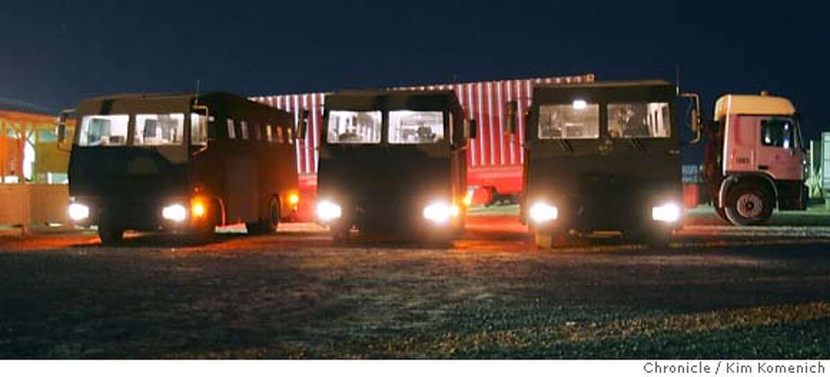 Three "rhinos" await passengers at Camp Stryker. The armored truck behind the rhinos carries passengers' bags and cargo from the airport to the International Zone. Soldiers and civilian contractors board the "Rhino", a heavily armored Winnebago-looking bus and begin a heavily guarded convoy from Camp Stryker at the Baghdad Airport to the International Zone in downtown Baghdad. The three Rhinos were escorted by two helicopters and several Bradley fighting vehicles. San Francisco Chronicle Photo by Kim Komenich 9/23/05