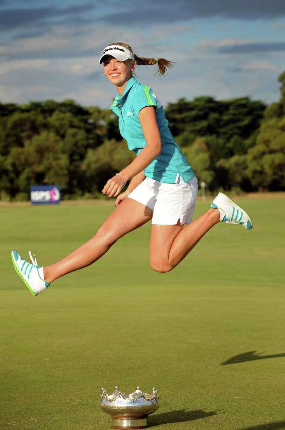 Jessica Korda imitates her father with a scissor-kick jump over the winner's trophy.