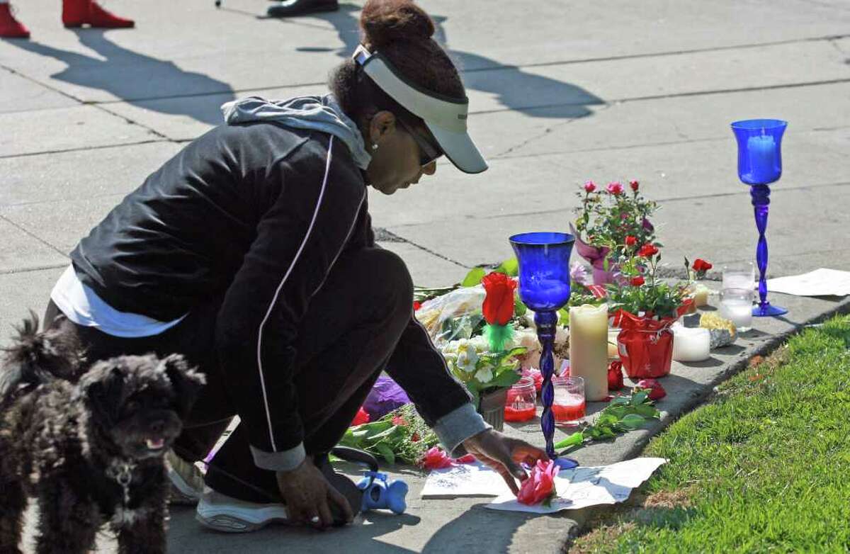 Donzaleigh Abernathy places a flower at a memorial outside the Beverly Hills Hilton Hotel on Sunday, Feb. 12, 2012, in Beverly Hills, Calif. Houston, who ruled as pop music's queen until her majestic voice and regal image were ravaged by drug use, erratic behavior and a tumultuous marriage to singer Bobby Brown, died Saturday, Feb. 11. She was 48. (AP Photo/Ringo H.W. Chiu)