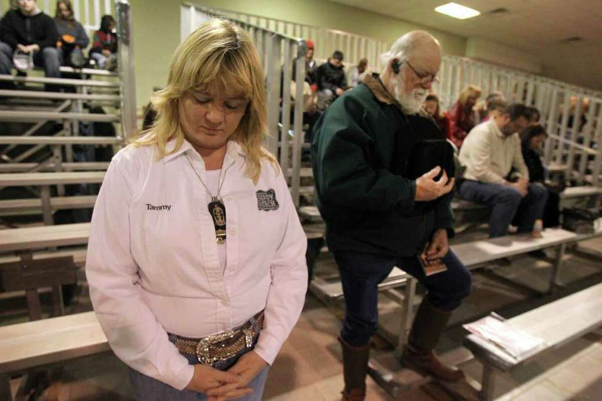 Tammy Carpenter (left) and Charlie Wilson (right) bow their heads during prayers at Cowboy Church on Sunday, Feb. 12, 2012 at the San Antonio Stock Show & Rodeo. The Sunday music and sermon was lead by Dr. Mark Jones.