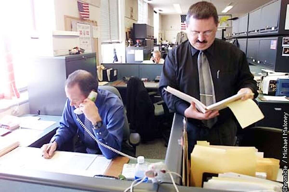COPS1-C-13MAR02-MT-MJM SFPD General Work's Lt Henry Hunter (right) looks over a case report near the desk of Inspecter Steve Venters (seated, left). Both work for General Work which handles the initial calls including violent crimes. CHRONICLE PHOTO BY MICHAEL MALONEY