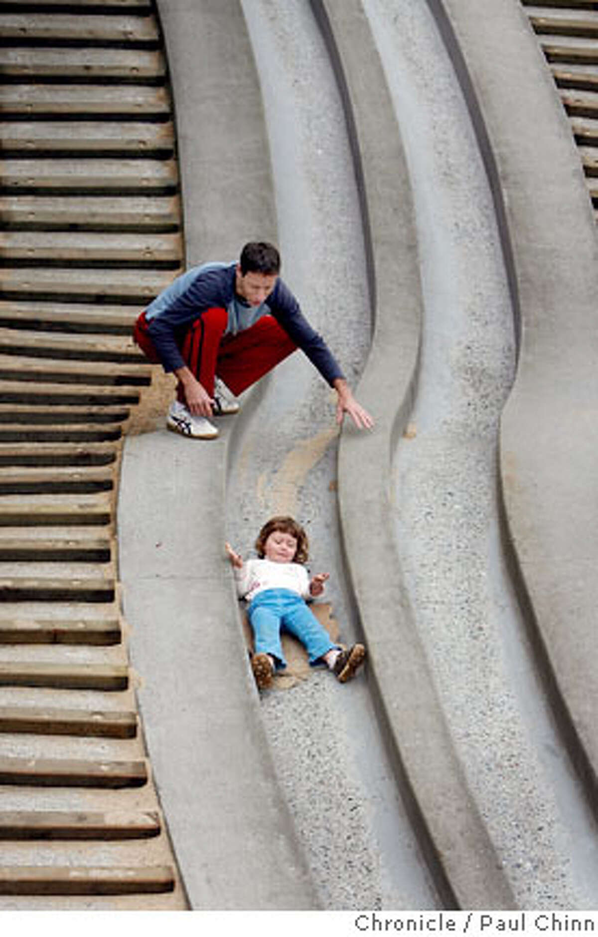 Gil Heiman helps his daughter Ines, 3, slip down the concrete slide at the Children's Playground which reopened at Golden Gate Park in San Francisco, Calif. on Saturday, July 14, 2007. The $3.8 million renovation project on the playground, that originally opened in 1887, took a year-and-a-half to complete. PAUL CHINN/The Chronicle ***Gil Heiman, Ines Heiman