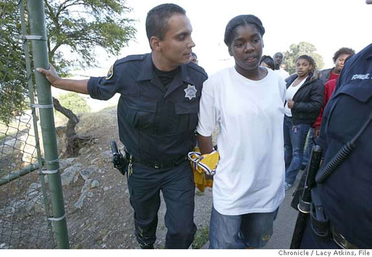 SFPD Officer Lewis Dejesus, from the Bayview Station, makes an arrest for assault after chancing the suspect through the Habor Housing Project, Thursday April 29, 2004. EDITOR NOTE--- The young girl in a minor and goes by the first name of "Crizma". A ride along with the Bayview Station after the death of Officer Isaac Espinoza, Thursday, April 29 2004, in San Francisco. LACY ATKINS / The Chronicle MANDATORY CREDIT FOR PHOTOG AND SF CHRONICLE/ -MAGS OUT