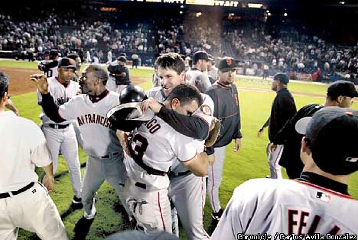 The Benito Santiago hugs Tim Worrell after the Giants take the field after winning against the Atlanta Braves at Turner Field in Atlanta, Ga., on Monday, October 7, 2002. (CARLOS AVILA GONZALEZ/SAN FRANCISCO CHRONICLE)