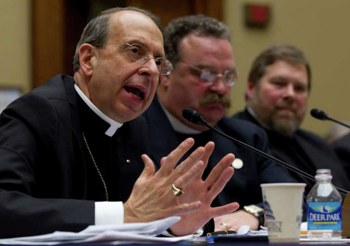 Reverend William E. Lori, Roman Catholic Bishop of Bridgeport, Conn., gestures while testifying on Capitol Hill in Washington, Thursday, Feb. 16, 2012, before the House Oversight and Government Reform committee hearing: "Lines Crossed: Separation of Church and State. Has the Obama Administration Trampled on Freedom of Religion & Freedom of Conscience." From left are, Lori, Reverend Dr. Matthew C. Harrison, President, The Lutheran Church Missouri Synod and C. Ben Mitchell, Graves Professor of Moral Philosophy Union University. (AP Photo/Carolyn Kaster)
