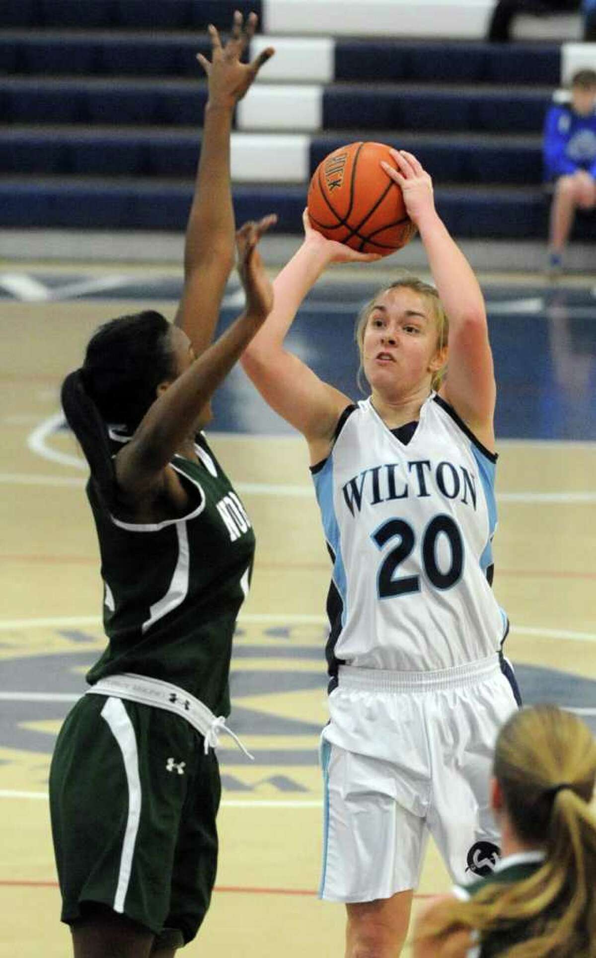 Wilton's Maddy Fulton takes a shot as she is defended by Norwalk's Emma Oyomba during Saturday's FCIAC Girls Basketball quarterfinal game at Wilton High School on February 18, 2012.