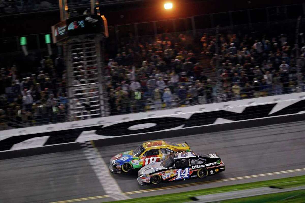 Kyle Busch (18) noses out Tony Stewart (14) at the finish line to win the Budweiser Shootout at Daytona International Speedway on Saturday night.
