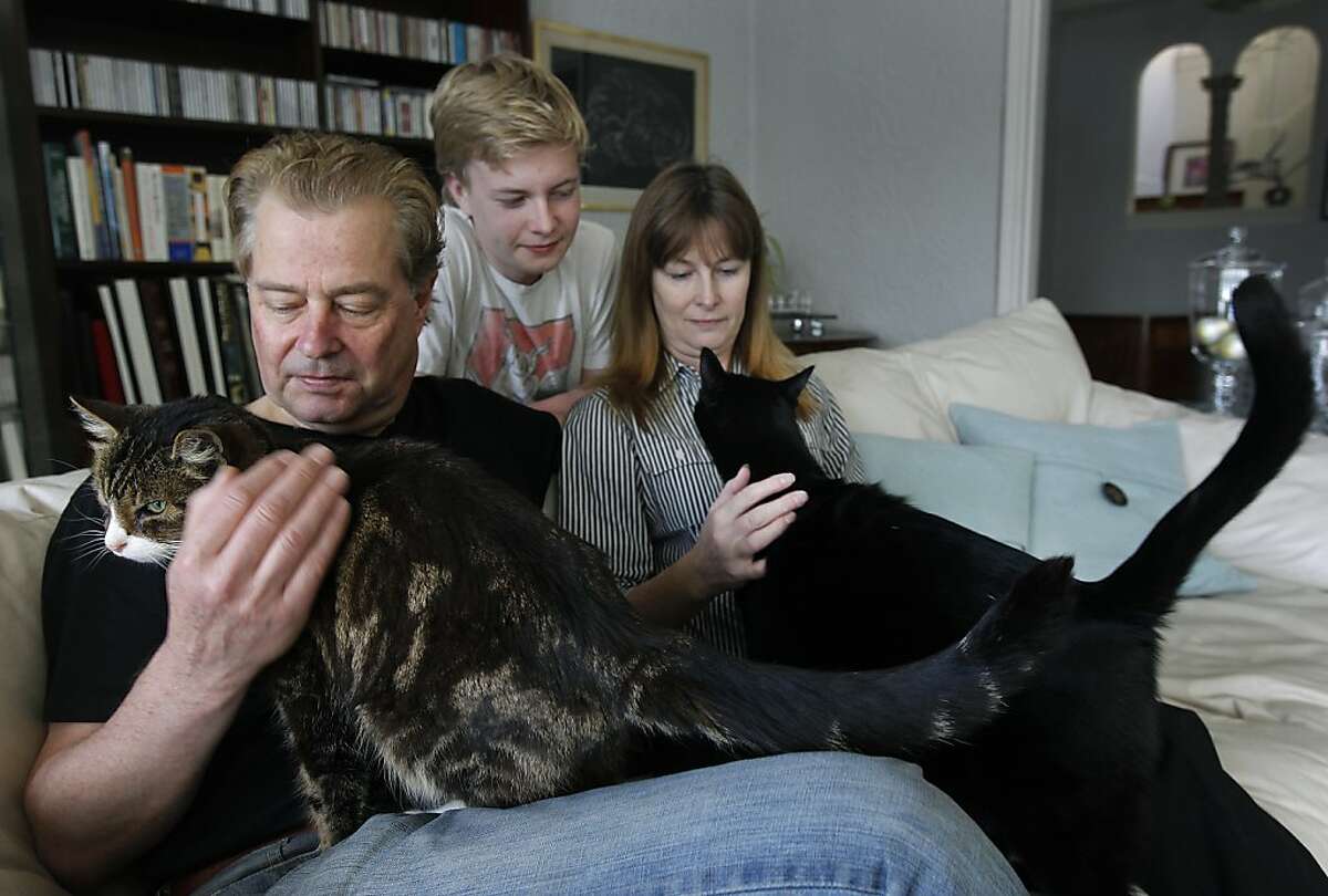 Jan (left) and Lena Samzelius and their 15-year-old son Tom pet the family cats Felix and Victor at their Marina district home in San Francisco, Calif. on Saturday, Feb. 18, 2012. The Samzelius' want to refinance their home loan but have been unable to identify exactly which bank owns the mortgage.