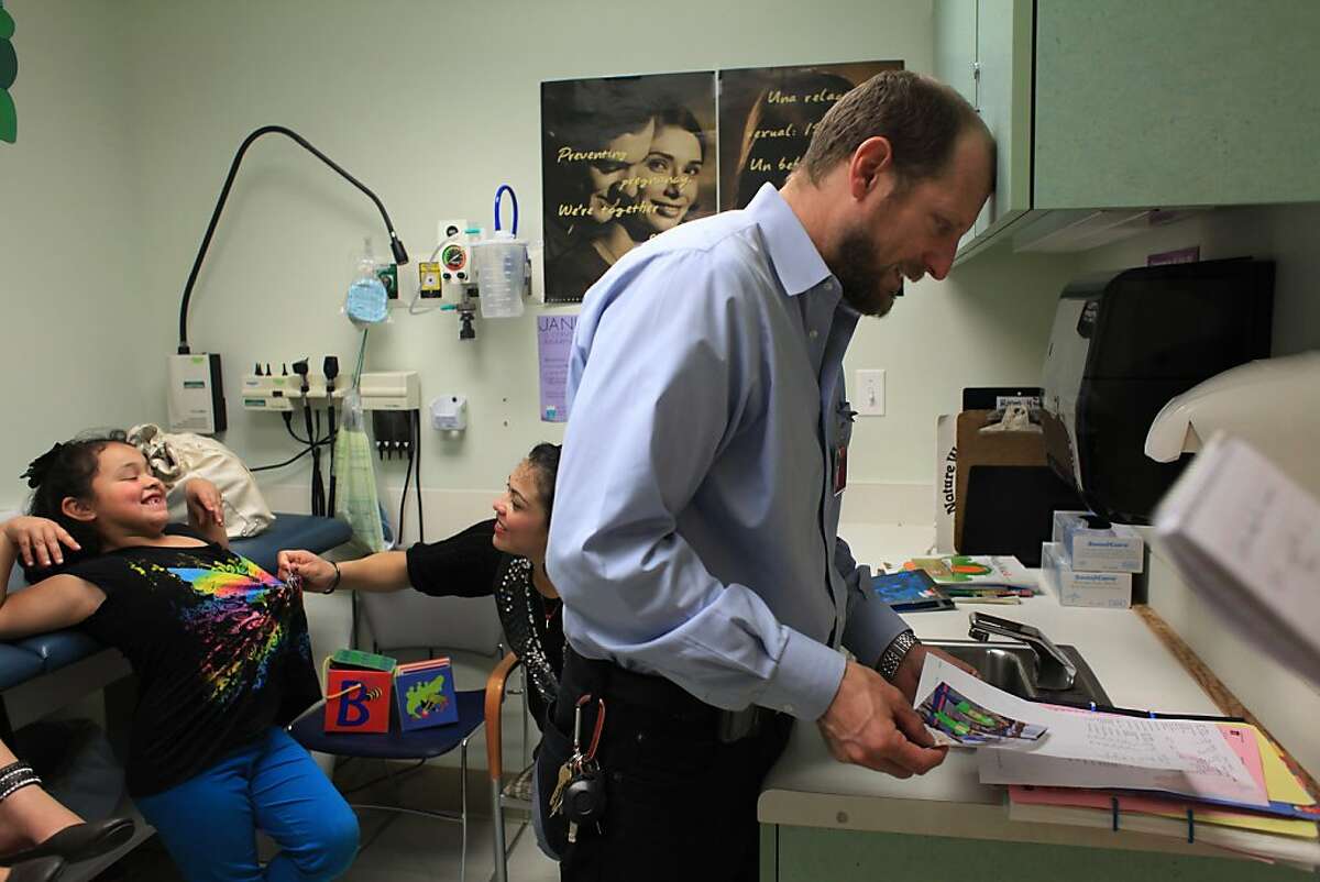 Dr. Robert Savio (right), chief of pediatrics at Highland looks through the medical files of Esmeralda Pena (left), 7, and Yazmin Pena (not shown), 10, during a visit to Highland Hospital on Wednesday, February 8, 2012 in Oakland, Calif.