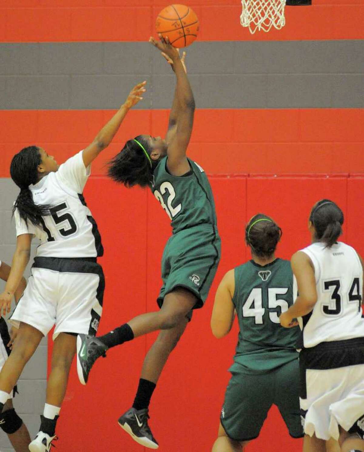 Reagan's Moriah Mack, center, shoots over Steele's Kyra Lambert, left, during a girls' high school basketball playoff game, Tuesday, Feb. 21, 2012, at Judson High School in Converse, Texas.