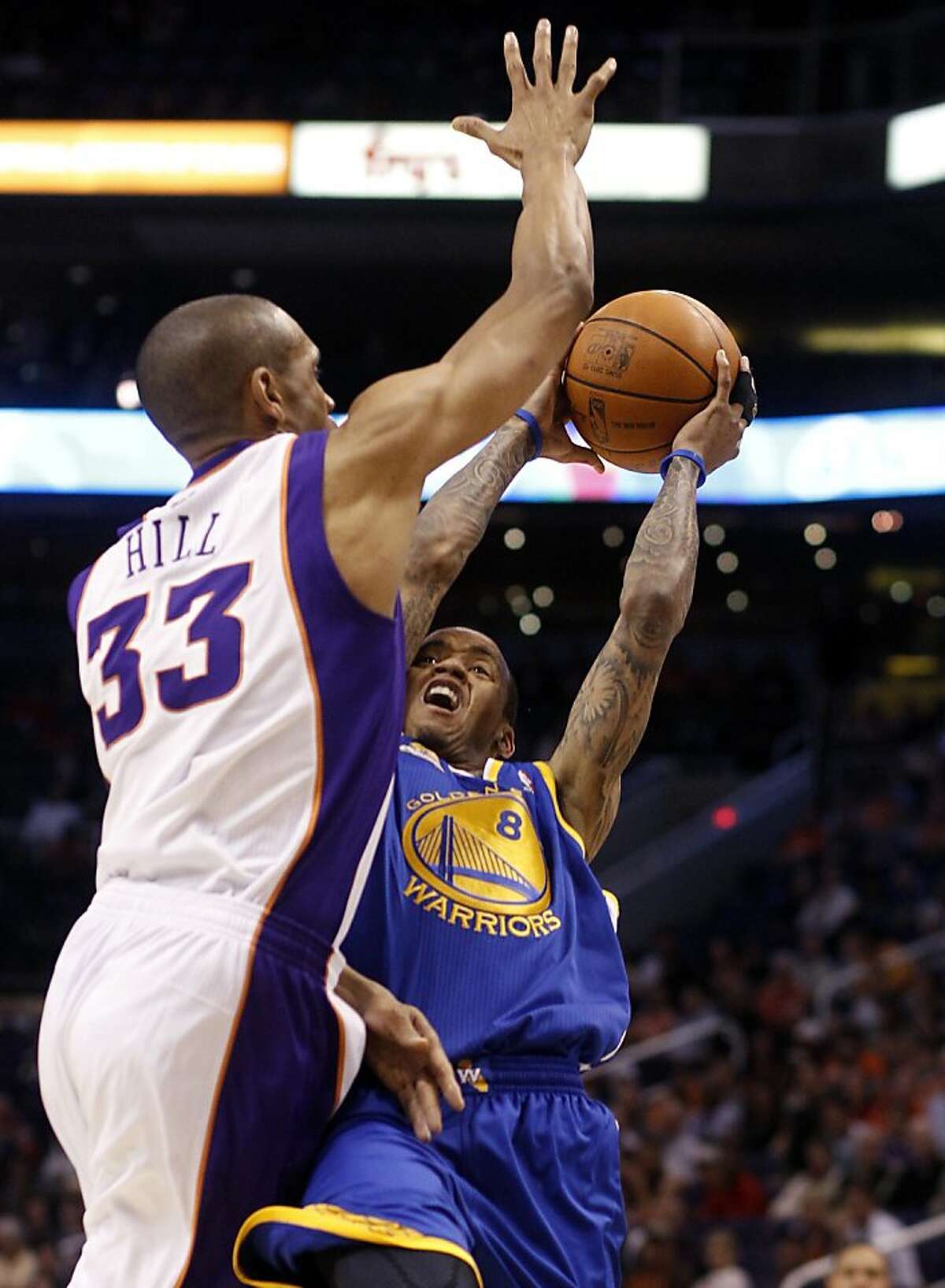 Golden State Warriors guard Monta Ellis, right, throws up a shot as he collides with Phoenix Suns forward Grant Hill (33) during the first quarter of an NBA basketball game Wednesday, Feb. 22, 2012, in Phoenix.
