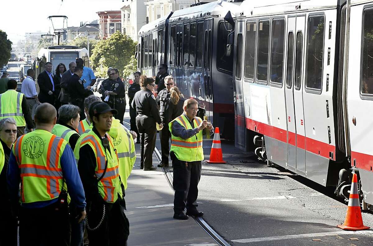 Investigators on the scene of an N Judah MUNI train, on Thursday Feb. 23, 2012, in San Francisco, Ca., which was involved in an accident at the corner of Irving and 2nd streets. According to witnesses a woman walking a dog tried to cross over a coupling that connects two train cars while at a stop, when the train began to moved and pulled the woman a half block down the street, pinning her under a car. The woman was taken to the hospital with non-life threatening injuries.