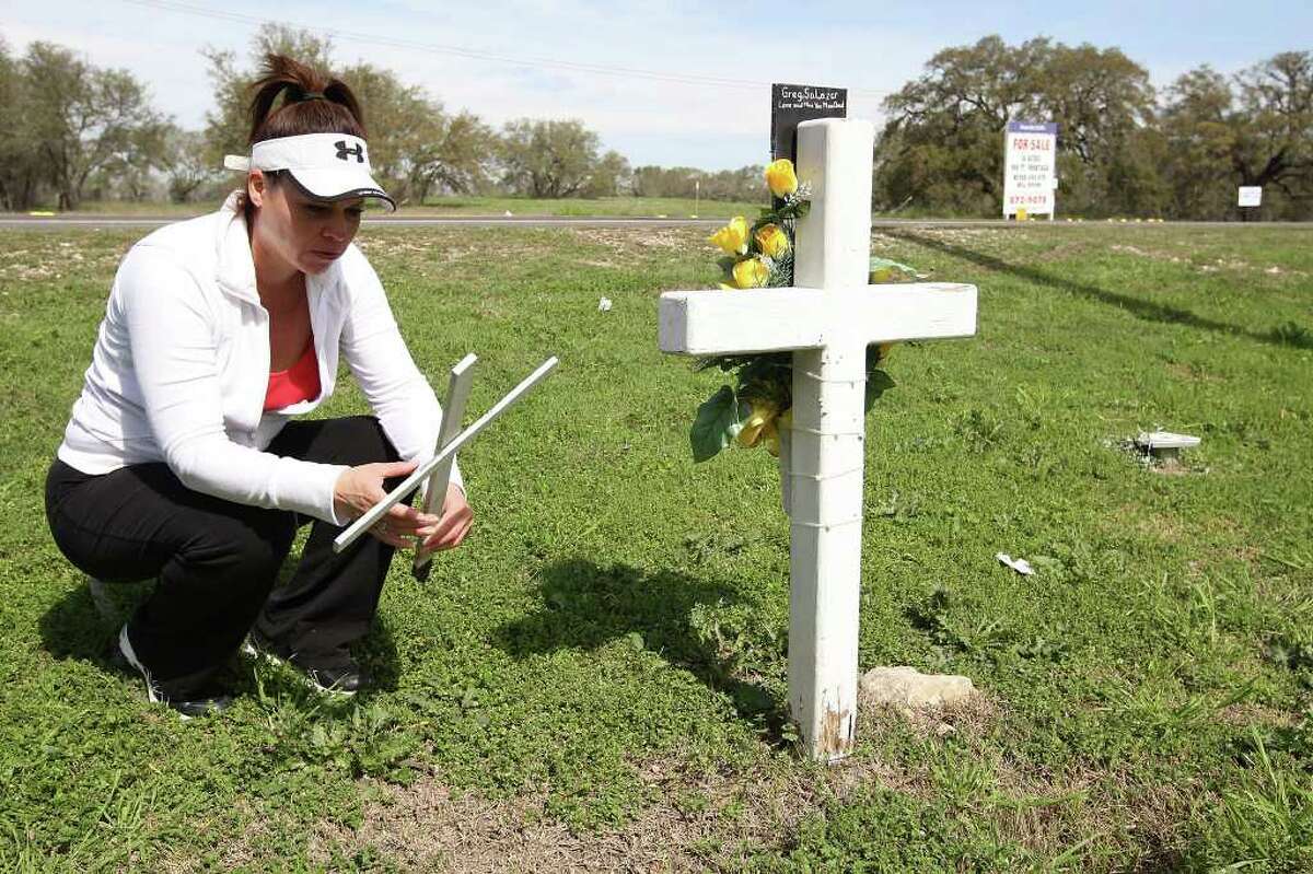 METRO -- Margot Salazar, 44, holds one of the crosses at a roadside memorial for her husband, Greg Salazar at the corner of Potranco Road and American Lotus, Thursday, Feb. 23, 2012. On the center right, is a base that used to hold a Texas Department of Transportation sign in memory of her husband. On March 2008, Salazar was riding his motorcycle by that intersection when struck by a hit-and-run driver. Jose Luis Morales was later convicted of intoxication manslaughter. The memorial was purchases by the victim's parent through a TxDOT program. Jerry Lara/San Antonio Express-News