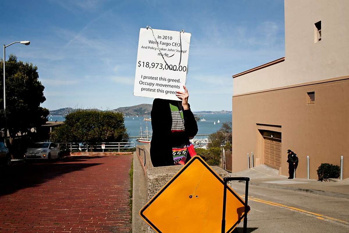 A woman held a sign protesting Wells Fargo CEO John Stumpf outside his home on Larkin and Chestnut streets Saturday during a Occupy Bernal Heights' movement in San Francisco, February 26, 2012. The group were turned away by "concerned citizens," left, blocking the entrance to the building. Jason Henry/Special to The Chronicle